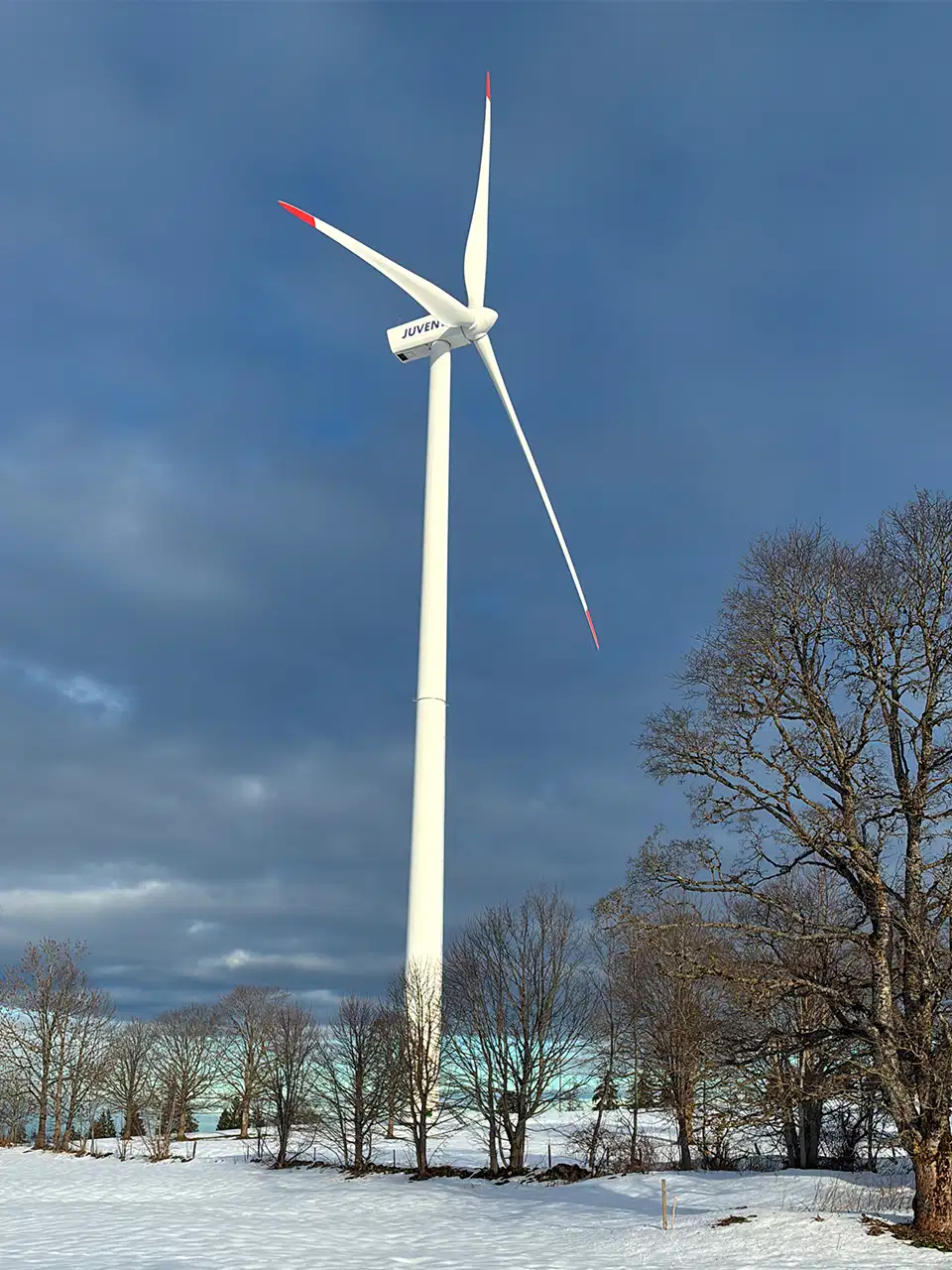 Éolienne du Mont-Crosin derrière un muret de pierres, en hiver